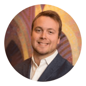 Smiling businessman in a suit at a networking event with a vibrant geometric background, conveying professionalism and approachability.
