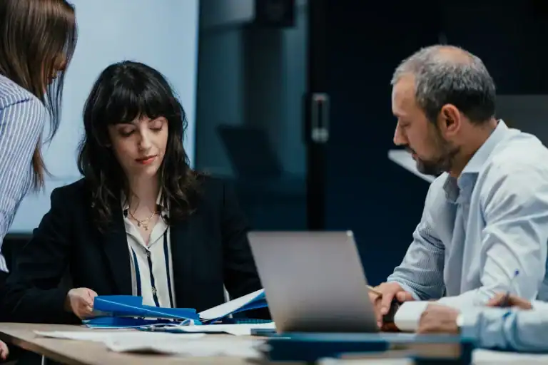 team reviewing performance reports during business meeting with laptop and documents