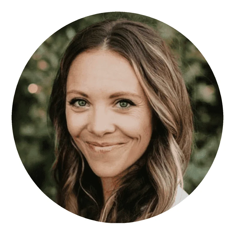 Portrait of a smiling Caucasian woman with wavy brown hair, green eyes, and a natural outdoor backdrop for a vibrant, engaging profile image.