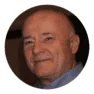 Elderly Caucasian man smiling in a professional headshot, wearing a dark suit against a soft-focus background, conveying trust and experience.