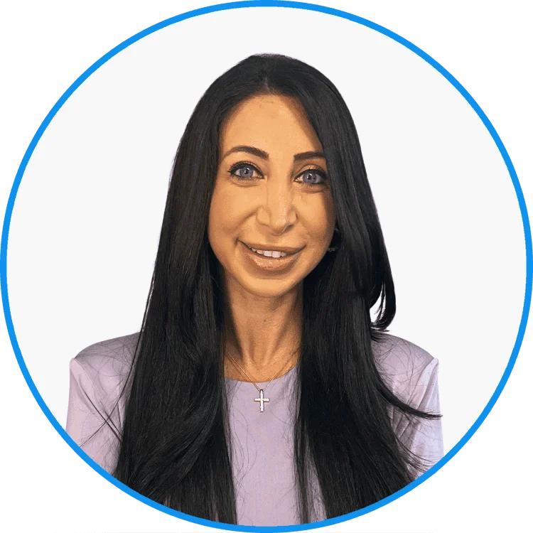 Professional portrait of a smiling woman with long black hair wearing a lavender blouse and a cross necklace, presented in a circular frame.
