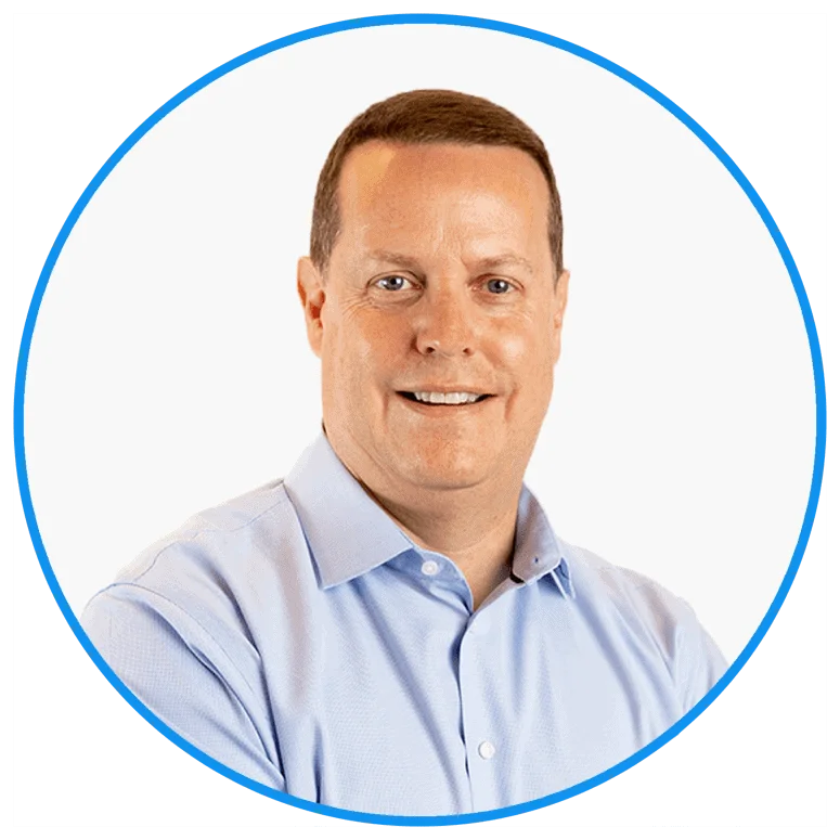 Professional headshot of a smiling middle-aged man wearing a light blue shirt against a white background, framed in a blue circle.