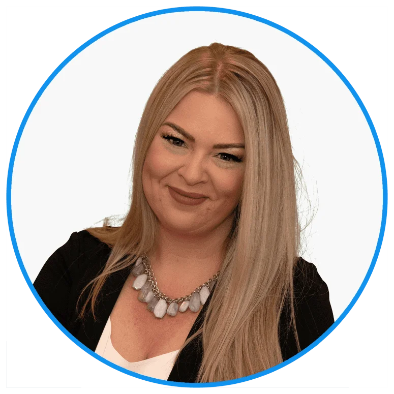 Professional blonde woman smiling, wearing a black blazer and a stylish gray necklace, isolated on a white background with a blue circular border.