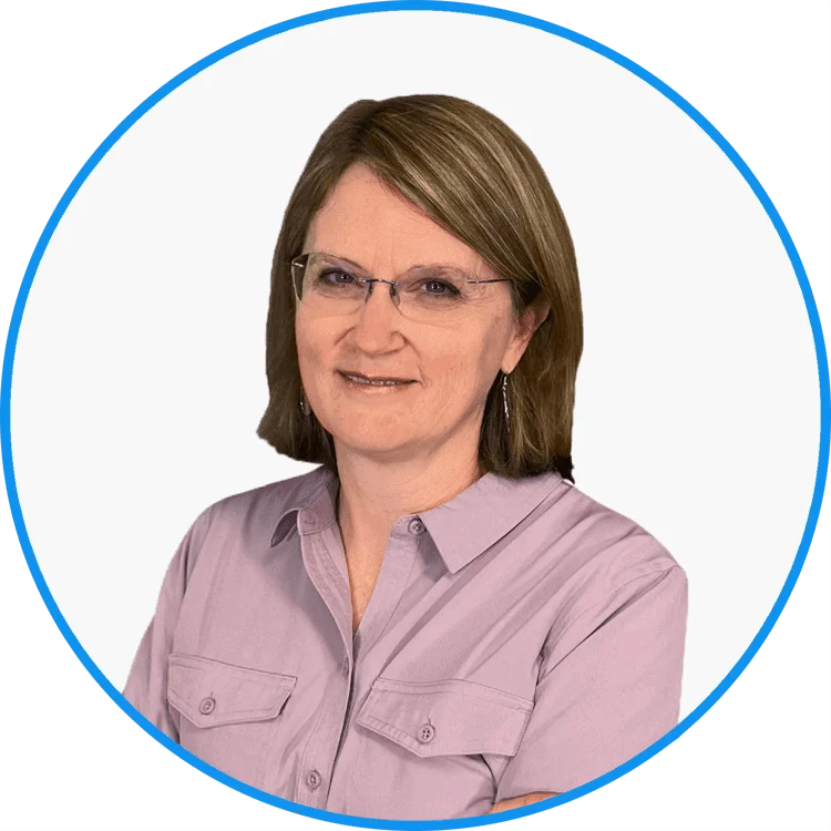 Mature professional woman wearing glasses and a lavender shirt, smiling confidently against a white background.