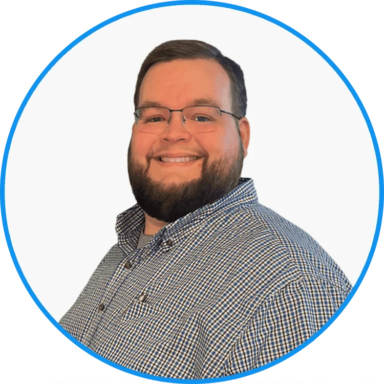 Smiling professional man in glasses wearing a checkered shirt, set against a plain white background with blue circular border.