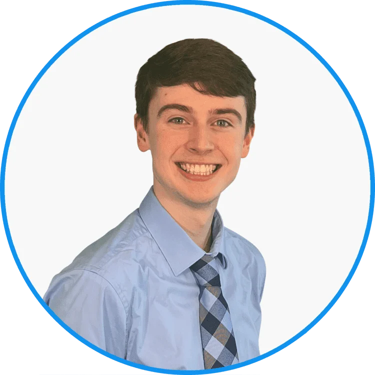 Young professional man smiling, dressed in a light blue shirt and checkered tie, white background, ideal for corporate profiles.