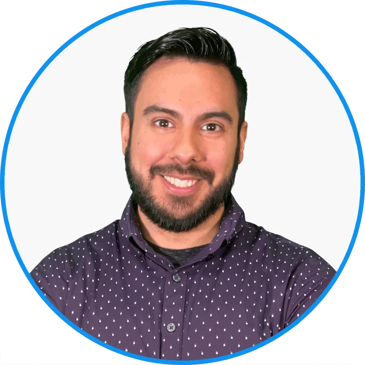Smiling man with a beard wearing a purple polka-dot shirt, professional headshot with a clean white and blue circular background.