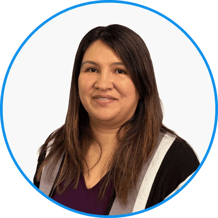Professional headshot of a smiling woman with long brown hair, wearing a purple top and striped cardigan, set against a green background.