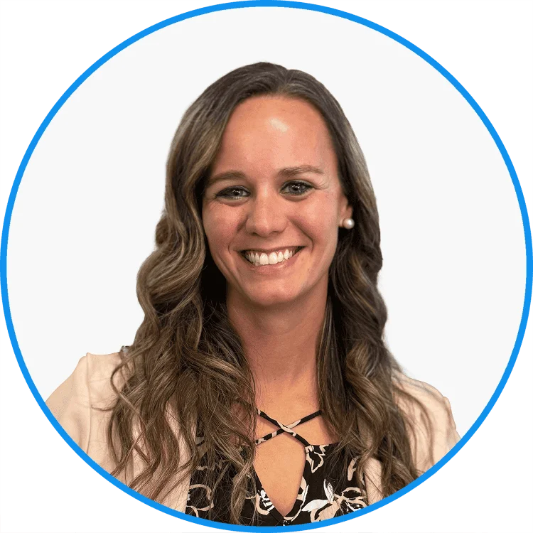 Professional woman smiling, oval frame, wearing black floral blouse and necklace, for corporate profile use.