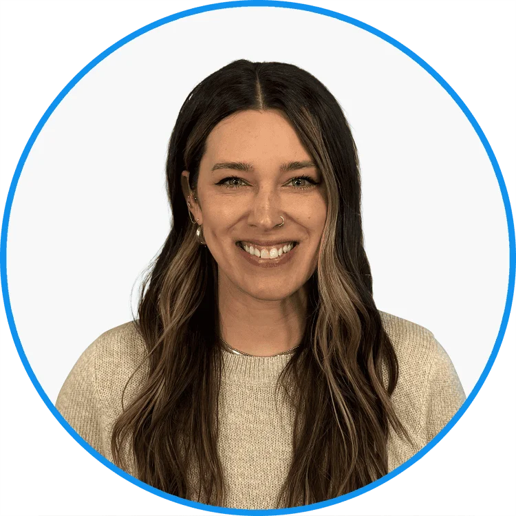 Smiling young woman with long wavy hair and a nose ring, wearing a beige sweater, set against a white background framed by a green circle.