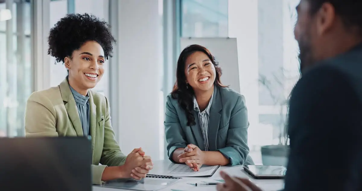 Diverse team of professionals engaging in a cheerful business discussion in a modern office setting, enhancing teamwork and communication.