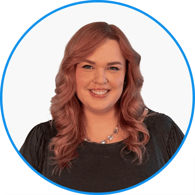 Professional woman with wavy, medium-length hair smiling in a black blouse, wearing a silver necklace, set against a white background.