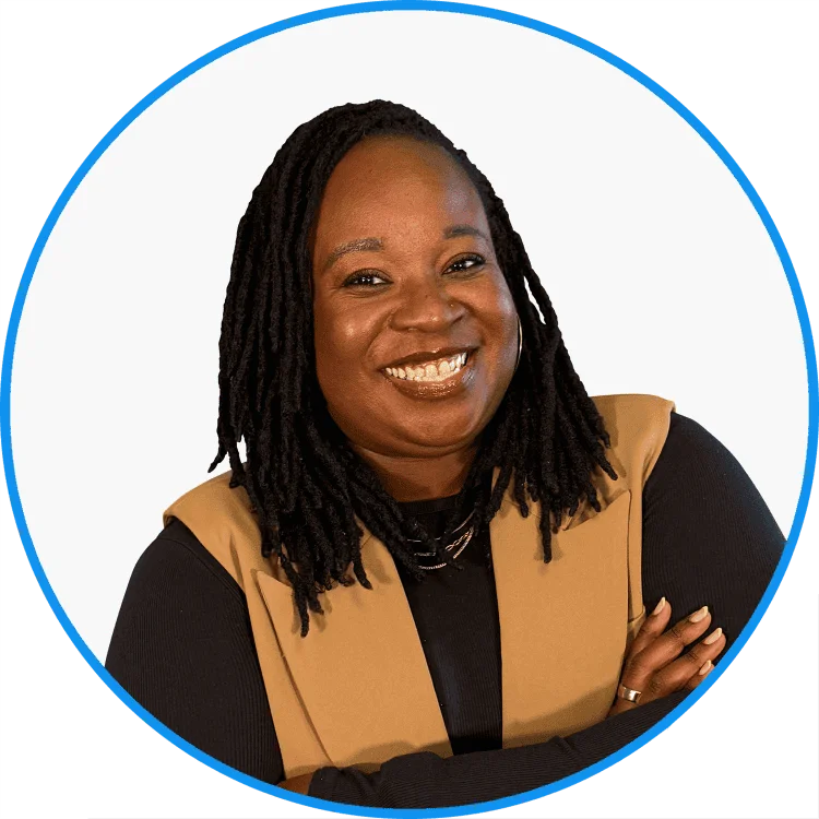African-American woman with joyful expression wearing a beige vest, styled with black necklace, against a plain background.