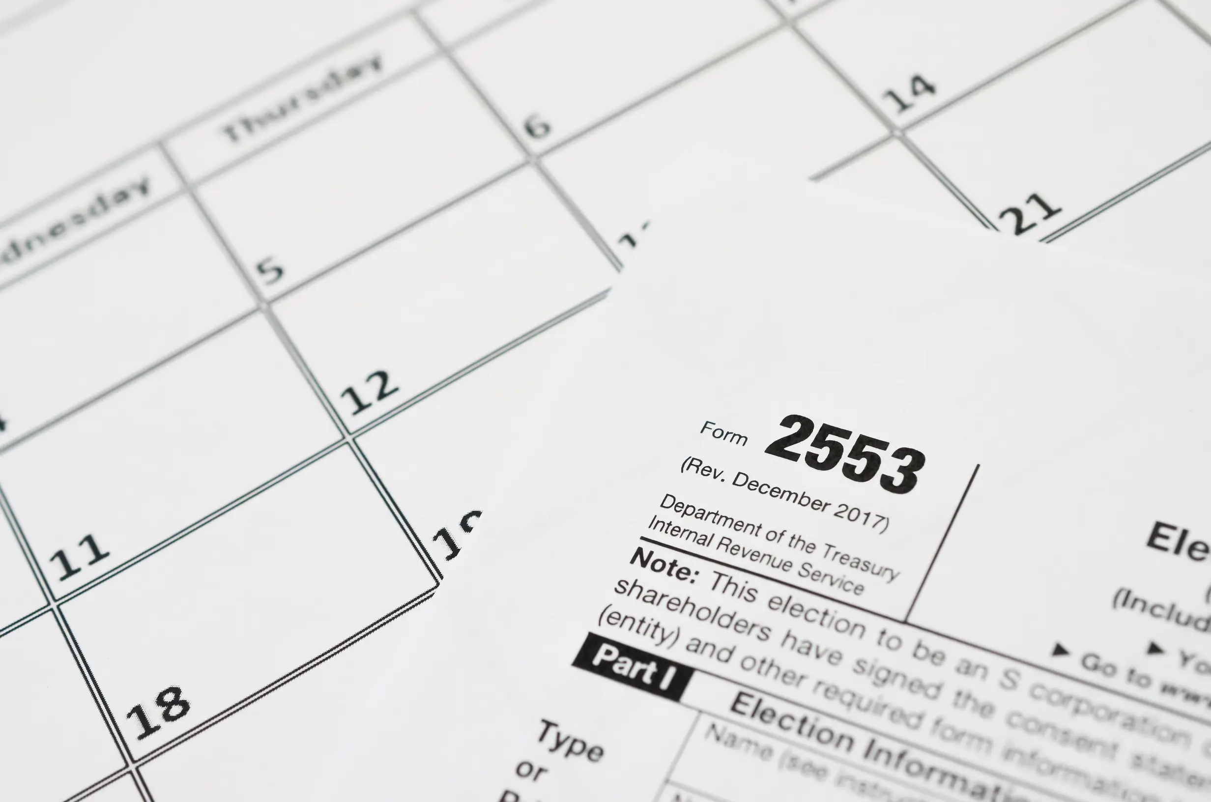 IRS Form 2553 Election by a Small Business Corporation tax blank lies on empty calendar page. Tax period concept.